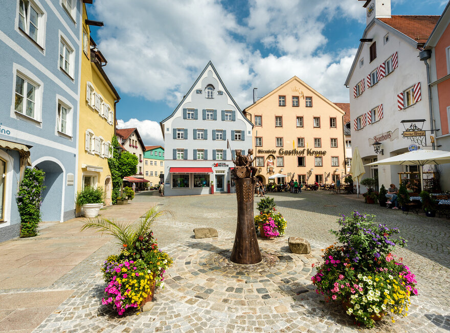 Der Schrannenplatz in Füssen mit historischen Gebäuden und Blumenkästen. Ein idyllischer Ort im Herzen der Stadt.