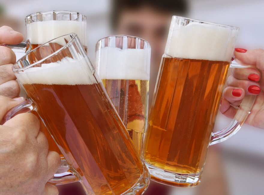  Das Bild zeigt eine Gruppe von Menschen, die ihre Biergläser in die Höhe halten, mit dem Fokus auf die schaumigen Kronen der Biere. Die Personen sind wahrscheinlich beim Feiern oder genießen eine gesellige Zusammenkunft.