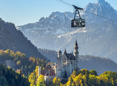 Eine Kabine der Tegelbergbahn gleitet am Schloss Neuschwanstein vorbei. Im Hintergrund ist der majestätische Säuling (2047m).