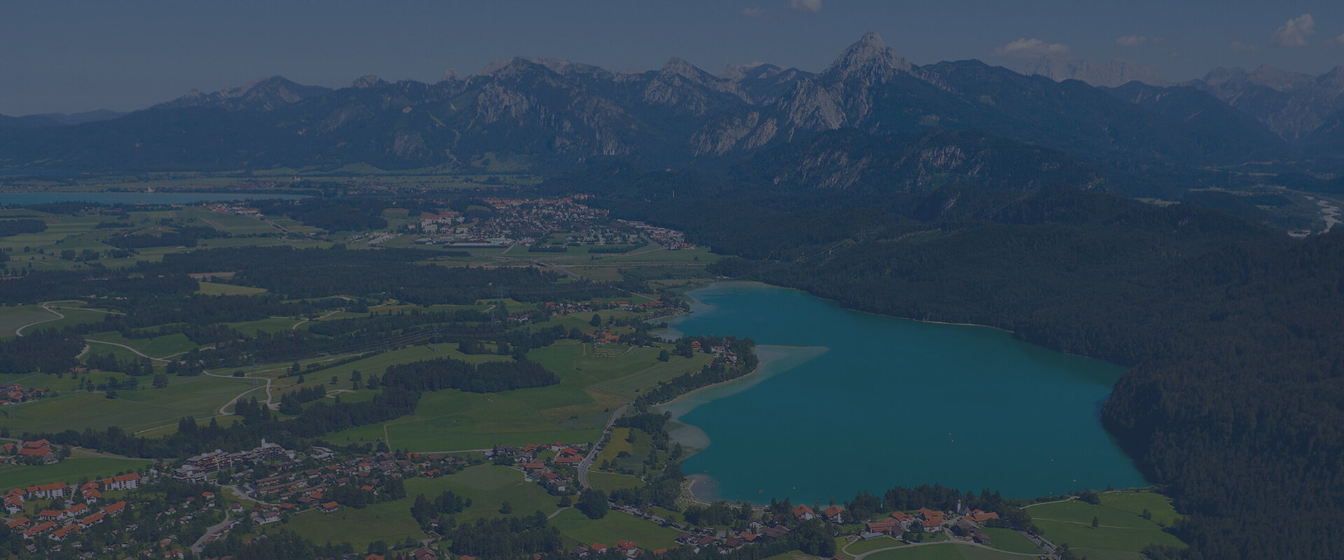 Hintergrundbild: Luftbild von Füssen mit Ammergebirge, Weißensee und Forggensee